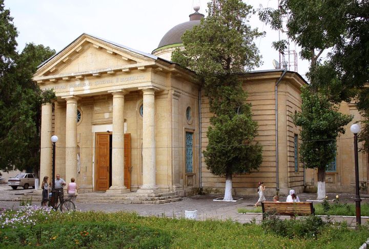 A domed sandstone church with a portico of four Tuscan columns and heavily rusticated walls.
